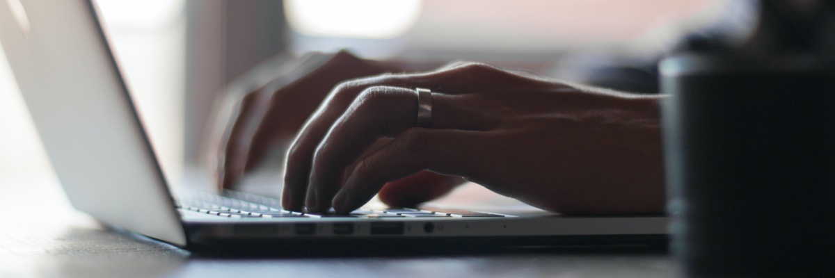 Mann tippt in die Tastatur eines Laptops